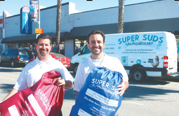 Aaron and Matt Simmons, founders of Curbside Laundries, holding wash and fold pickup and delivery bags outside their Super Suds laundromat